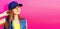Summer portrait of beautiful young woman model wearing blue baseball cap on vivid pink background, banner blank copy space for