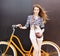 Summer Portrait of the beautiful young woman stands at the vintage bicycle. The wind blows her hair. Dark background. Warm