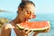 Summer portrait funny girl in red glasses holding huge slice of watermelon and bites him with pleasure.