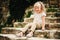 Summer portrait of happy child girl sitting on stone stairs