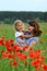 Summer portrait of happy cuddling mother and daughter in the poppies field