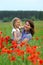 Summer portrait of happy cuddling mother and daughter in the poppies field