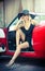 Summer portrait of stylish blonde vintage woman with long legs posing near red retro car. Fashionable attractive fair hair female