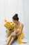 Summer portrait of young brunette woman with straw basket of yellow flowers