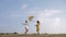 Summer relaxation, cheerful little girlfriends play with kite outdoors on background of blue sky during a weekend in