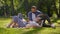 Summer romance. Happy couple in love enjoying picnic in public park, man feeding woman with ripe strawberries