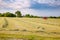 Summer rural landscape with tractor collecting hay in the field