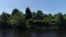 Summer rural landscape with wooden house near lake. Shot. Sunny day in a russian village with a small house surrounded