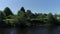 Summer rural landscape with wooden house near lake. Shot. Sunny day in a russian village with a small house surrounded