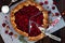 Summer rustic raspberry galette with ice cream on wooden table.