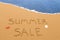 Summer sale written in the sand