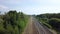 Summer scenery of empty long railways laying along green line of forest trees.