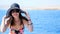 Summer, sea, portrait of a beautiful young brunette woman wearing a bathing suit and sun hat, sunglasses, standing on a