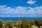 Summer seascape on Cypus. View to the bay with green grove in front and blue clouded sky. View from the hill. Latchi village on