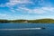 Summer seaside landscape view of a fast going speedboat with blue sky and land horizon.