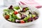 Summer season salad with salad leaves, tomatoes, cucumbers, Italian herbs and cheese in a bowl on a table