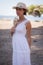 Summer Serenity: Girl in White Dress with Straw Hat and Flowers by the Sea