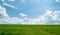 Summer shining meadow with blue sky and fluffy clouds