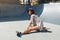 Summer. Skater Girl Sitting On Skateboard At Skatepark Portrait. Female Teenager In Casual Outfit Looking At Camera.