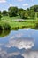 Summer sky and trees reflected in lake water