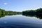 Summer sky and trees reflected in lake water