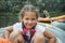 In the summer, a small girl with pigtails sits in a boat