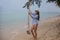 Summer solar portrait of fashion of a way of life of the young stylish woman,sitting on a swing on the beach,carrying lovely fashi