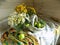 Summer still life made of wicker basket, wild flowers and green apples