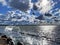 Summer storm at sea dramatic fluffy clouds on blue dark sky  birds fly water wave splash on pier at Baltic sea on horizon Tallinn