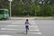 In the summer, on the street, a little girl crosses the road on a pedestrian crossing