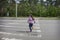 In the summer, on the street, a little girl crosses the road on a pedestrian crossing