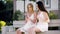 Summer sunny day, two young laughing women in dresses are sitting on a bench, resting and watching photos on the
