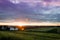 Summer sunset over humble farm and shack during peak harvest