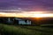 Summer sunset over humble farm and shack during peak harvest