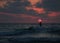 Summer sunset view of a beach under a cloudy sky with a single sup surfer silhouette