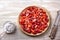 Summer tart with custard of baked milk and juicy fresh strawberries on light wooden background