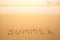 Summer - text written by hand in sand on a beach