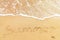 Summer text written on sandy beach and sea waves. Relaxing on tropical island. Summer vacation concept. Hello summer concept