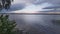 A summer thunderstorm is approaching the lake, and large thunderclouds are gathering. Reeds are growing in the water. View of the