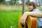 Summer time female portrait happy emotion face in garden outside space with acoustic guitar green grass everywhere
