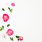 Summer time frame of pastel pink roses flowers and leaves on white background. Flat lay