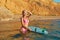 Summer time, holiday trip and surf sport idea. Pretty girl in sea water with board for surf. Mountain view on backdrop.