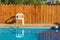 Summer time rustic relaxation space outskirts villa back yard with swimming pool blue water surface white plastic chair and wooden