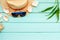 Summer travaling to the sea with straw hat, sun glasses, shells on mint green wooden background top view mock up