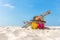 Summer Travel. Bikini and Flip-flops ,hat, fish star and bag near beach chair on sandy beach against blue sea and sky background,