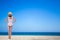 Summer and travel concept - back view of young beautiful woman in pink swimsuit posing at the beach with white sand - copy space