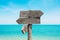 Summer travel destinations options.  Direction road sign with wooden arrows on beach and sea