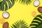 Summer tropical composition. Frame of Green tropical leaves of palm trees and monstera, coconut, orange on bright yellow