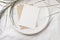 Summer tropical stationery still life scene. Dry date palm leaf on round marble tray. White table cloth in sunlight