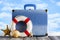 Summer vacation bag - suitcase, lifebuoy and shells on beach background